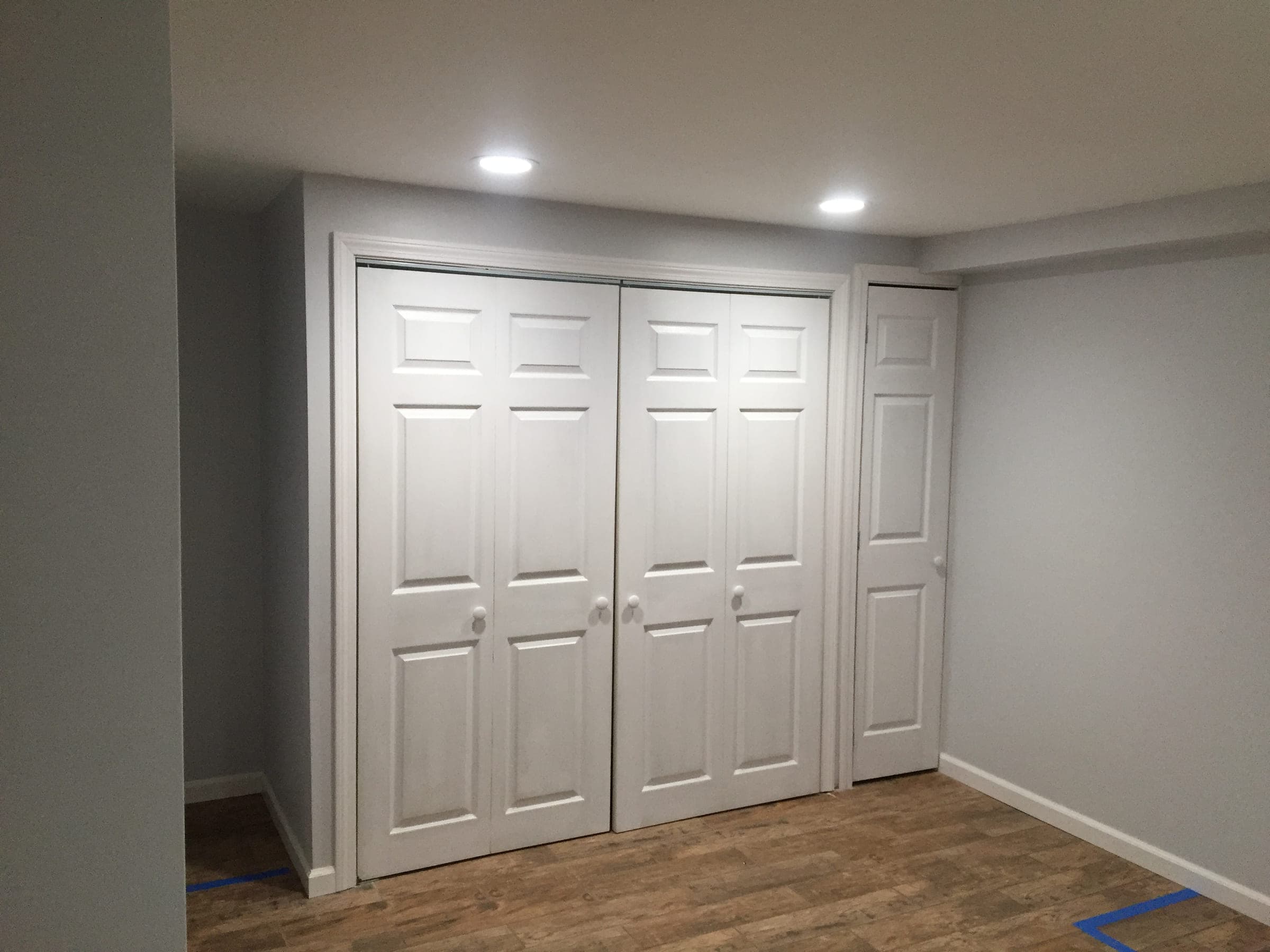 Finished basement with white six-panel closet doors, painted walls, recessed lighting and wood-effect plank flooring