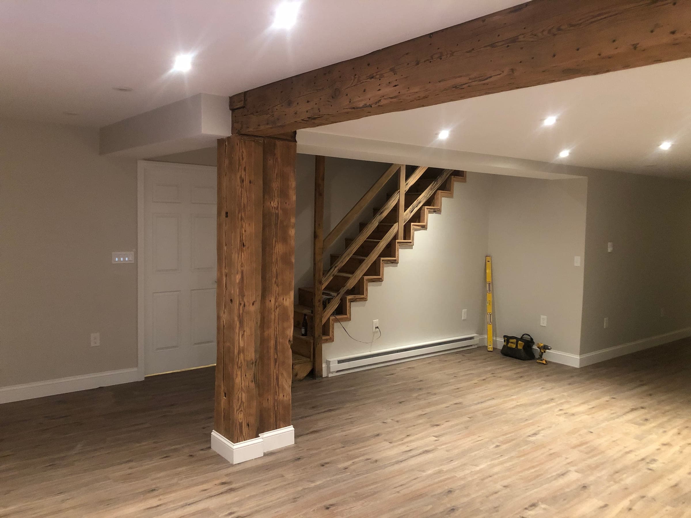 Finished lower-floor room with painted walls and trim, an exposed timber beam and a timber post