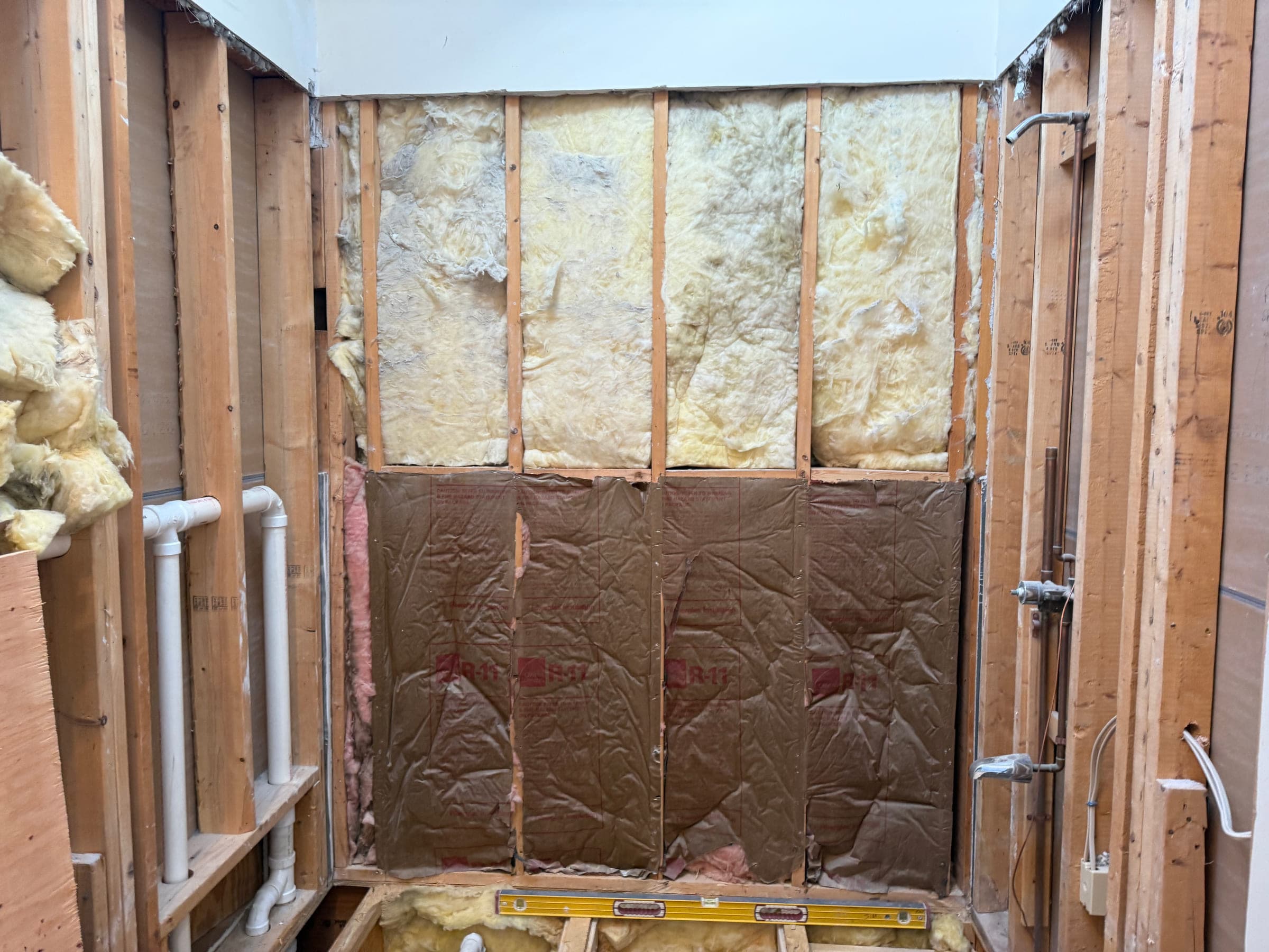 Bathroom walls insulated between the studs with rough plumbing run for a shower and a basin