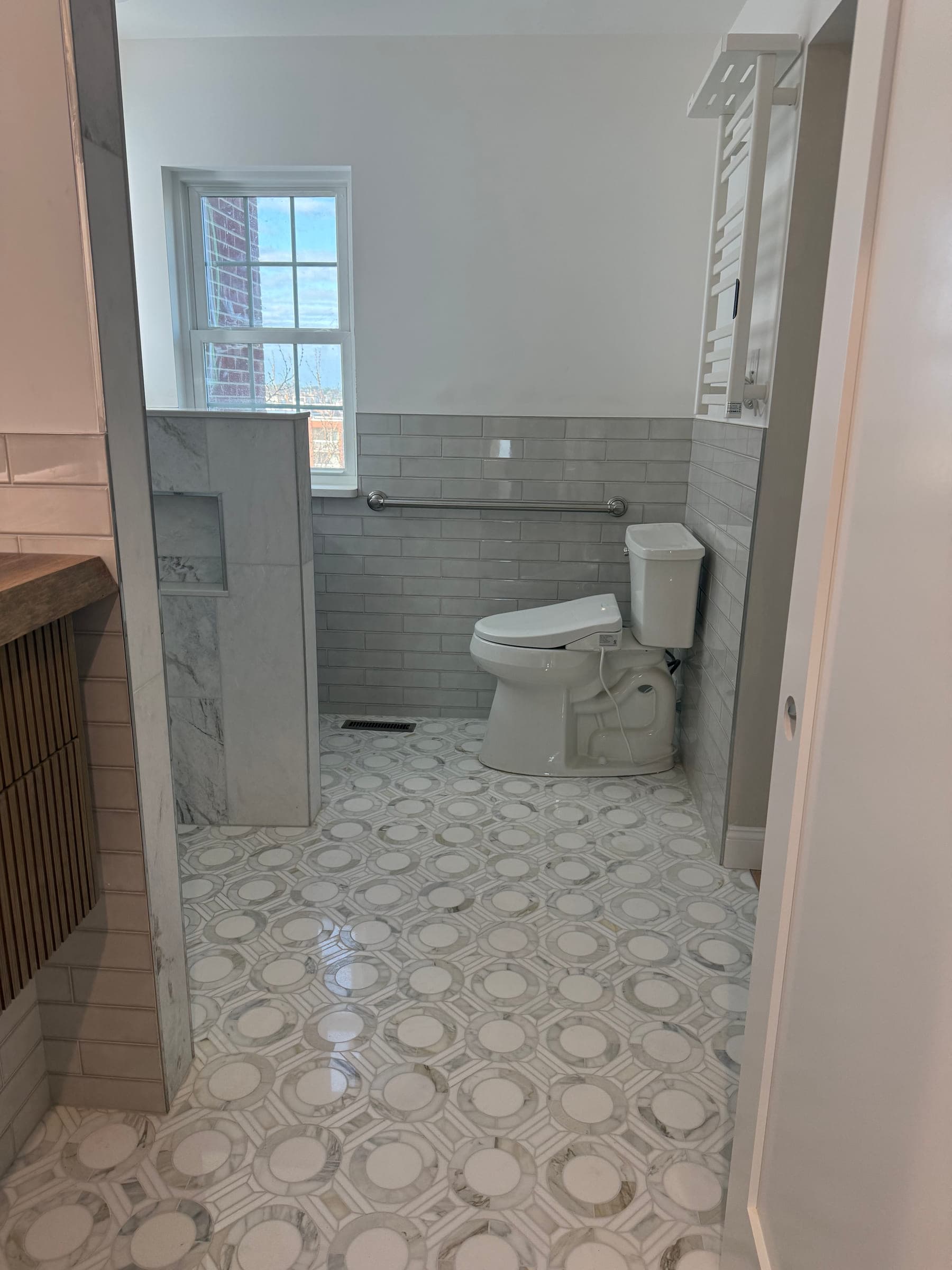 Finished bathroom with a tiled knee wall, ribbed tile wainscot and a patterned marble mosaic floor