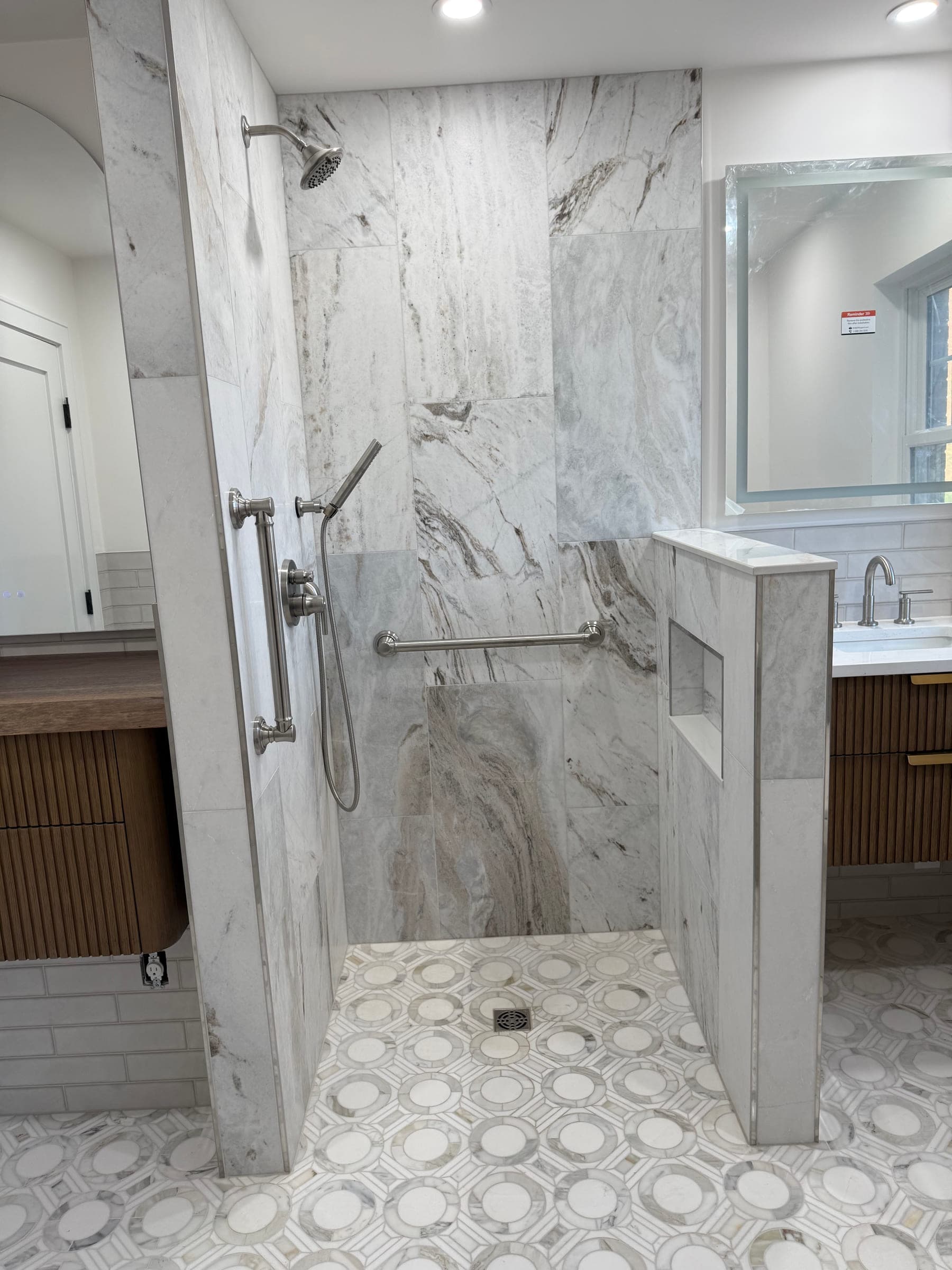 Full view of a finished bathroom with a curbless shower, tiled knee wall and vanity with mirror