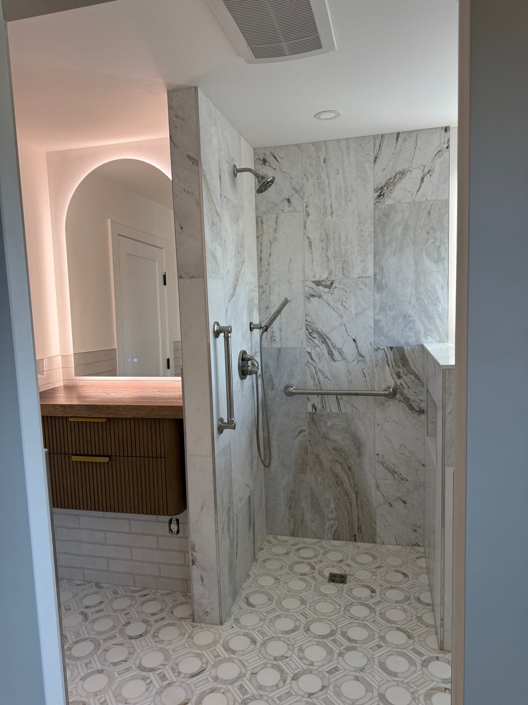 Wide view of a finished bathroom showing the walk-in shower, extractor fan and vanity beyond