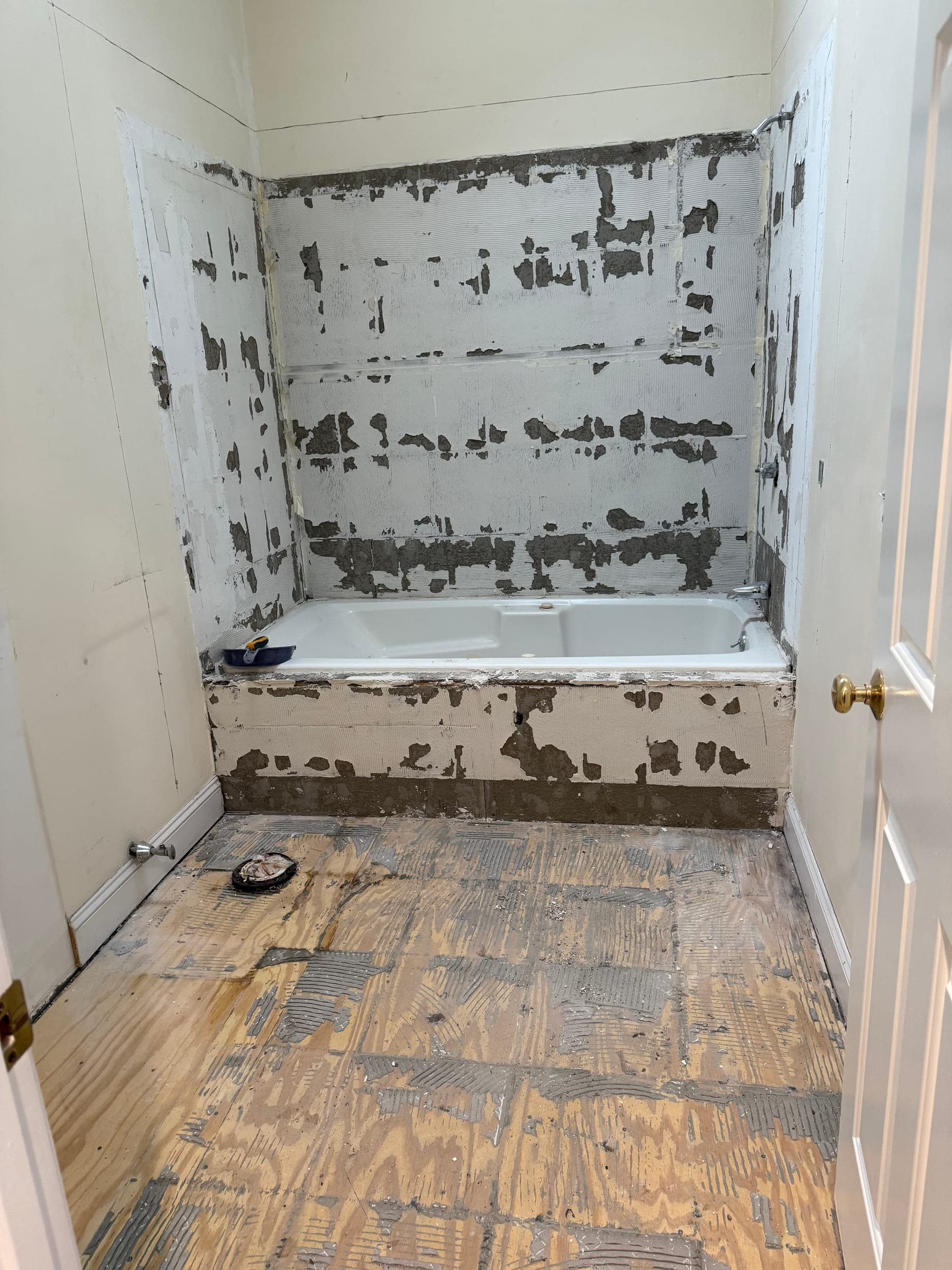 Bathroom with the wall tile stripped back to bare substrate and the floor covering removed, the bath still in place