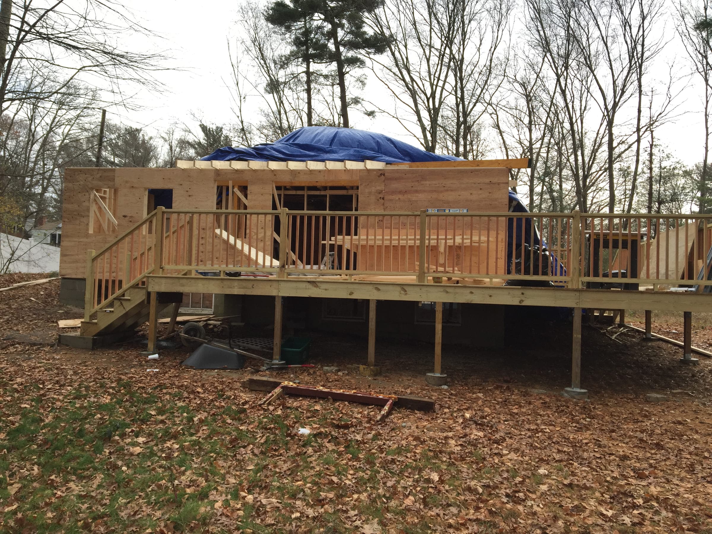 New timber-framed addition under construction above a newly built deck with railings and steps