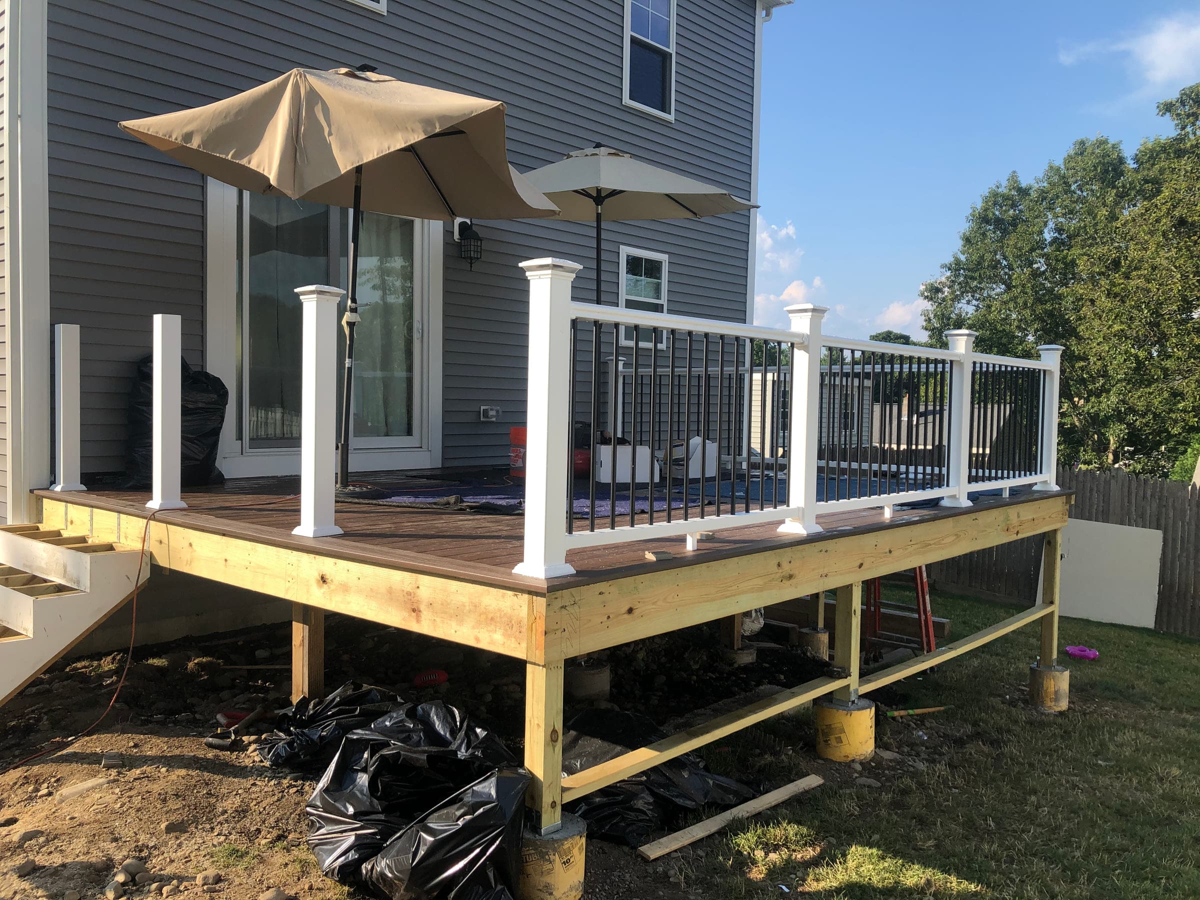 Deck with white railings and metal balusters fitted, the timber frame and posts still exposed below