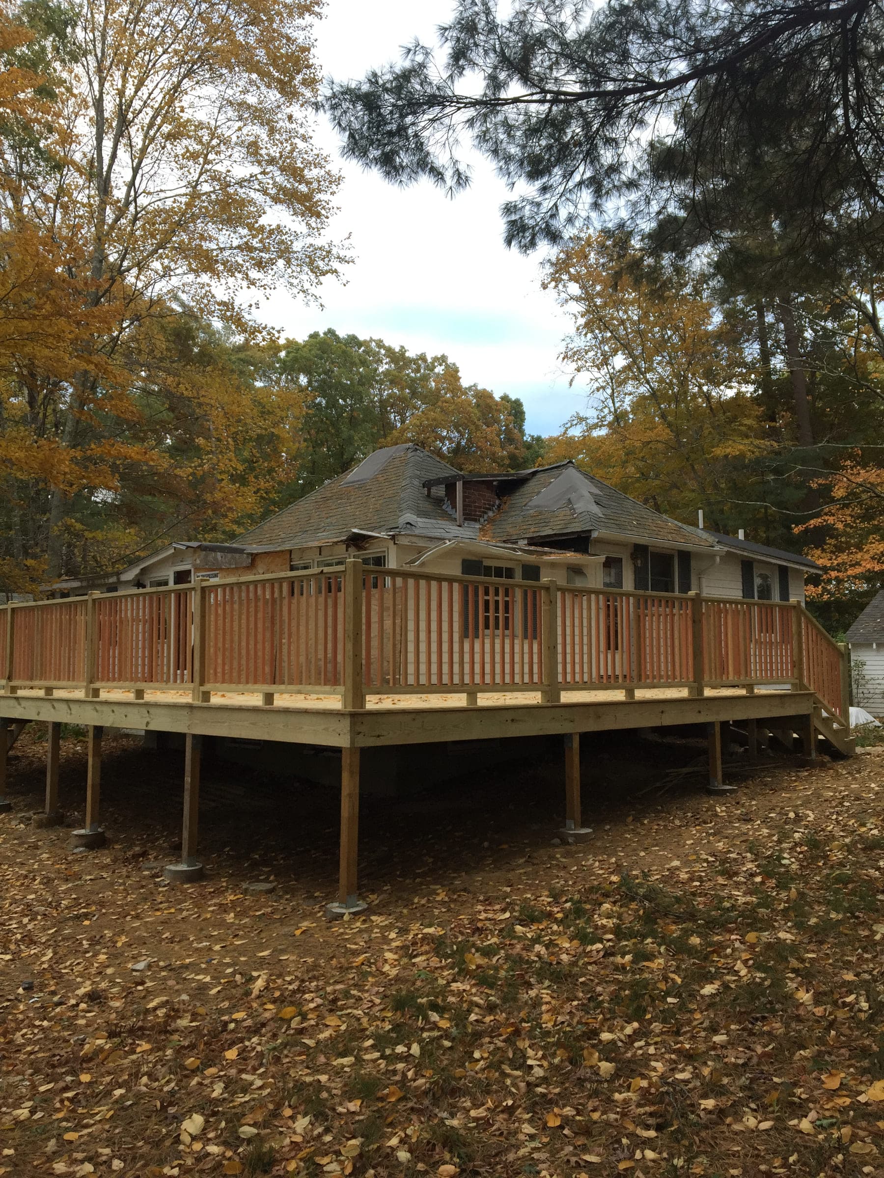 Large timber deck wrapping around a house, with railings and posts set on footings