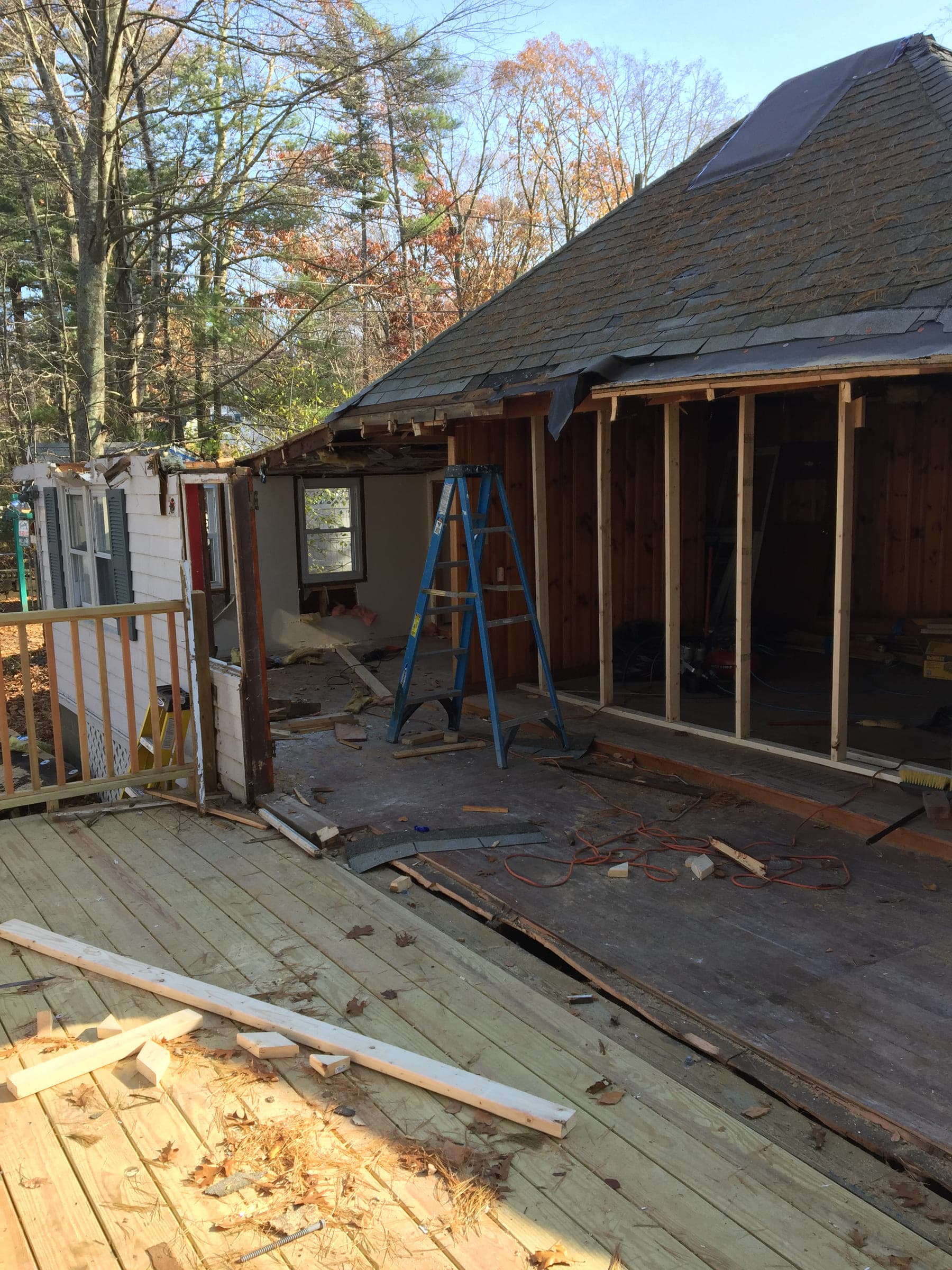 House wall stripped back to the studs during structural work, with the roof and the deck boards exposed